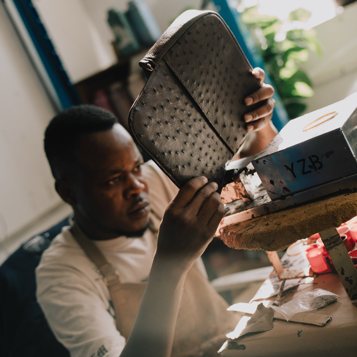 A Tuska artisan inspecting an ostrich leather bag in the atelier